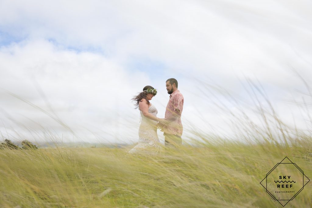 Bride and groom take photo in field in Waimea