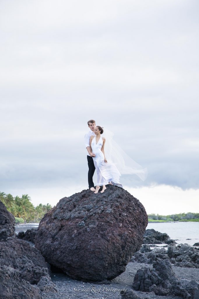 bride and groom climb on rock 