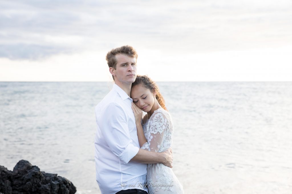 bride and groom hold each other on beach 