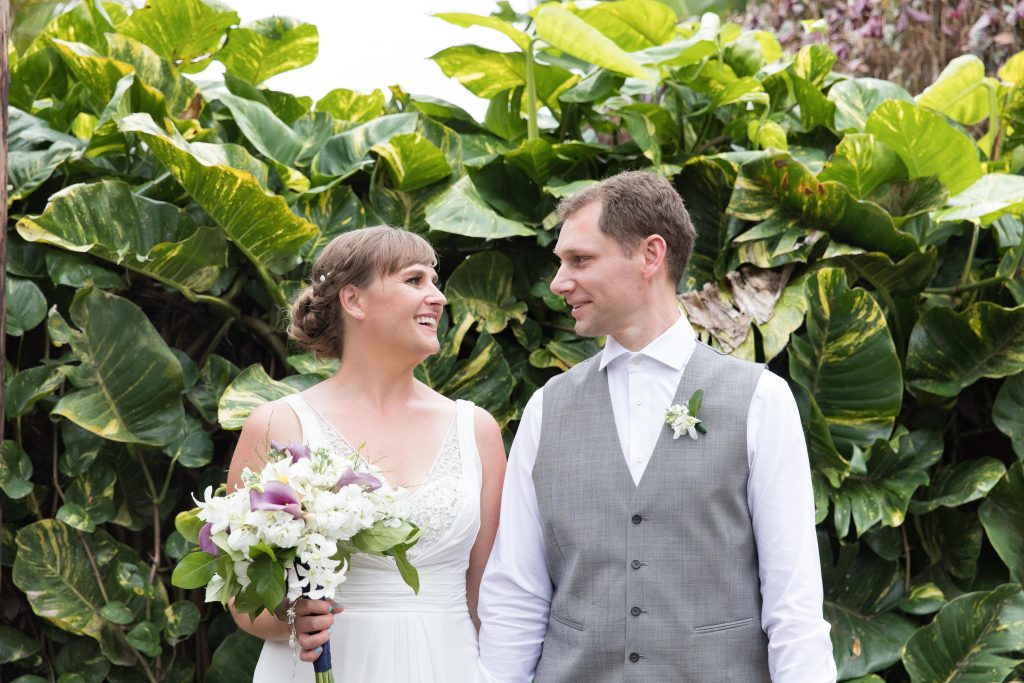 bride and groom in front of tropical plant at Kealakekua Bay Wedding Venue