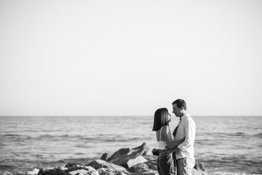 black and white of couple on rocks at beach proposal
