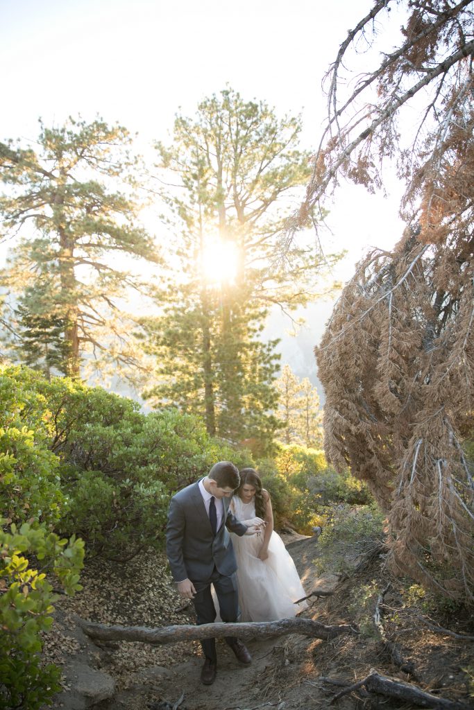 groom helps bride up hill Yosemite