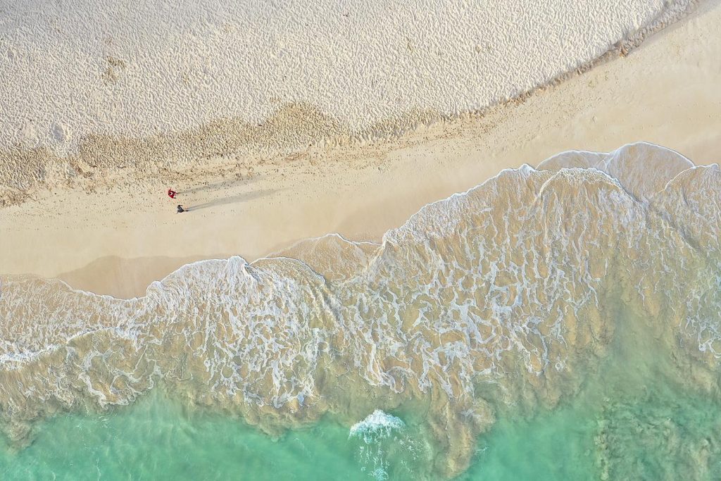 couple walking on the beach drone shot