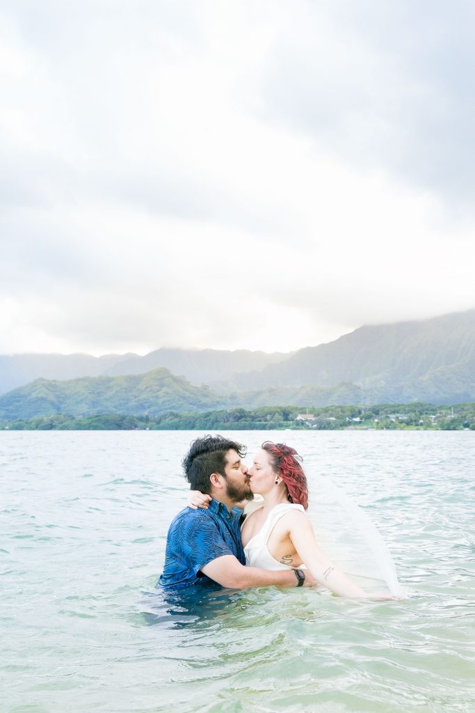 husband and wife kiss in ocean after Kualoa Secret Island Beach