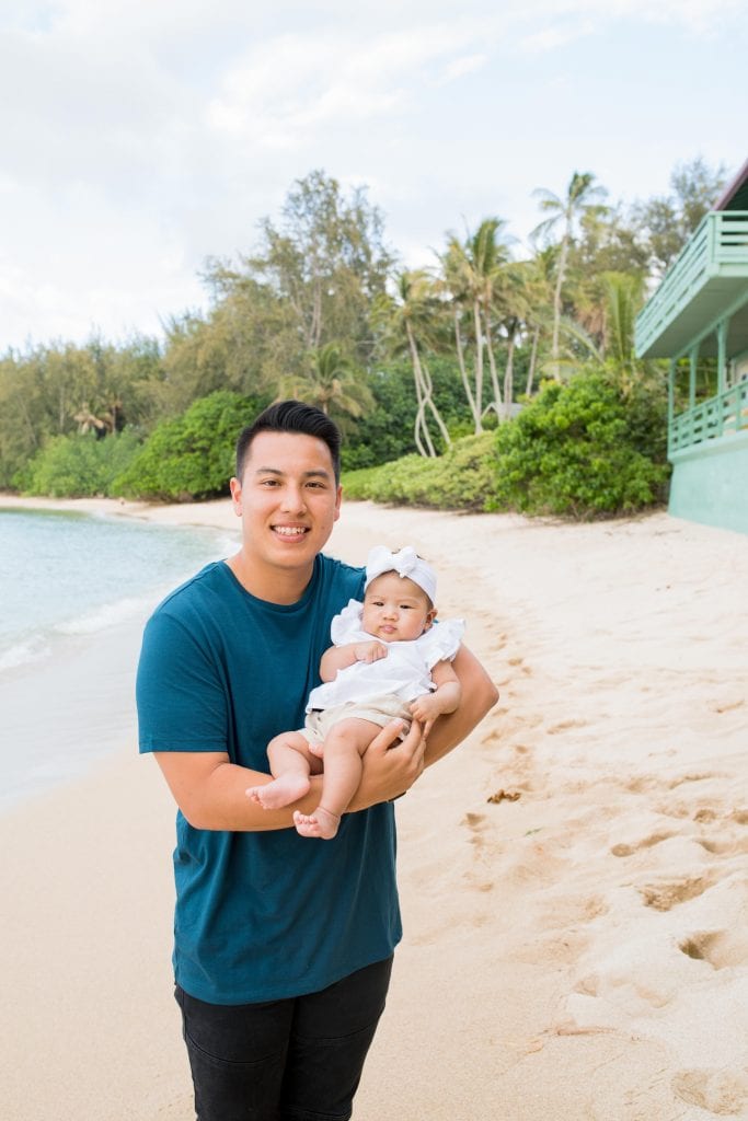 son holding baby on beach