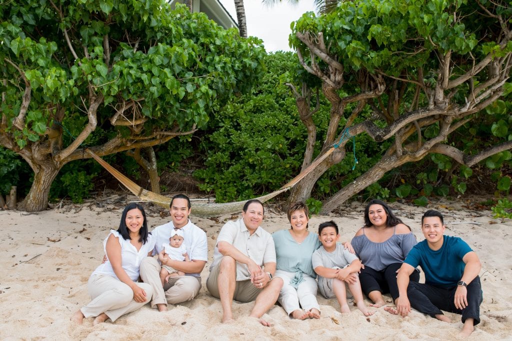 family sits together on beach